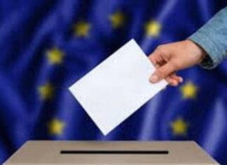 ΑΝΑΚΟΙΝΩΣΗ: 26-04-2024 Άνθρωπος ρίχνει ψηφοδέλτιο σε κάλπη με την ευρωπαϊκή σημαία στο φόντο.