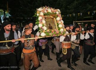 Πολυαρχιερατικός εσπερινός στην Παναγία Σουμελά στο Βέρμιο Αντίγραφο: Ομαδική παράσταση με παραδοσιακές φορεσιές και εικόνα με λουλούδια σε εκδήλωση Κυκλικής Δημοκρατίας.