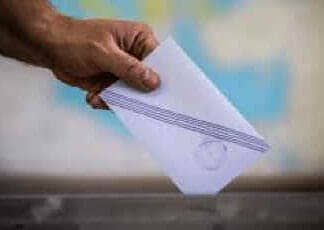 Ακρίβεια, Διαφθορά, Ανασφάλεια: Η Τριπλή Αποτυχία της ΝΔ Που Οδηγεί σε Πρόωρες Εκλογές! Άνθρωπος ρίχνει ψηφοδέλτιο σε κάλπη.