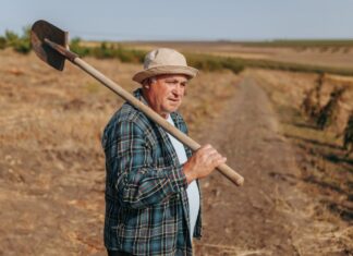 ΣΚΑΝΔΑΛΟ: Η Κυβέρνηση Κλέβει 217 Εκατομμύρια Ευρώ Από τους Αγρότες! Η Ελλάδα Μοναδική Αποτυχημένη στην Ε.Ε. Ανθρώπινος γεωργός με τσάπα στη φύση ραχούλα, ιδανική εικόνα για βιώσιμη και κυκλική δημοκρατία.