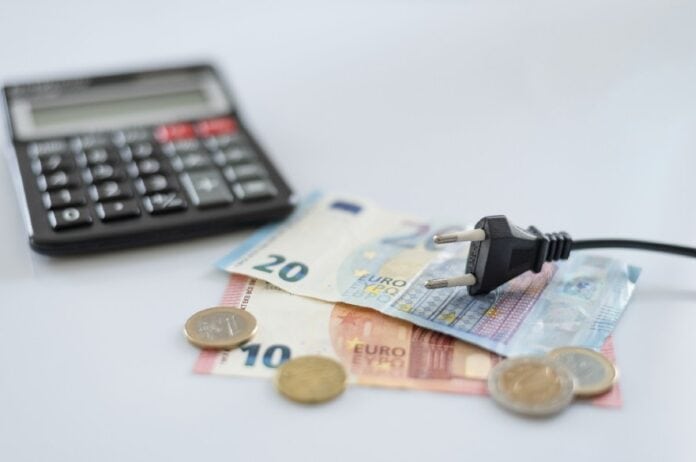 Οικονομία & Κυκλική Δημοκρατία. Οικονομικά εργαλεία και Κυκλική Δημοκρατία με εικαστικό ηλεκτρικό φορτιστή, ευρώ και νομίσματα.