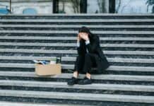 ΑΝΕΡΓΙΑ-ΡΕΚΟΡ ΣΤΙΣ ΓΥΝΑΙΚΕΣ ΚΑΙ ΤΟΥΣ ΝΕΟΥΣ – Η ΚΥΚΛΙΚΗ ΔΗΜΟΚΡΑΤΙΑ ΑΠΑΙΤΕΙ ΑΜΕΣΕΣ ΛΥΣΕΙΣ! Άνεργη γυναίκα καθισμένη σε σκαλιά με κουτί αποκατοίκηση, συμβολισμός οικονομικής δυσκολίας.