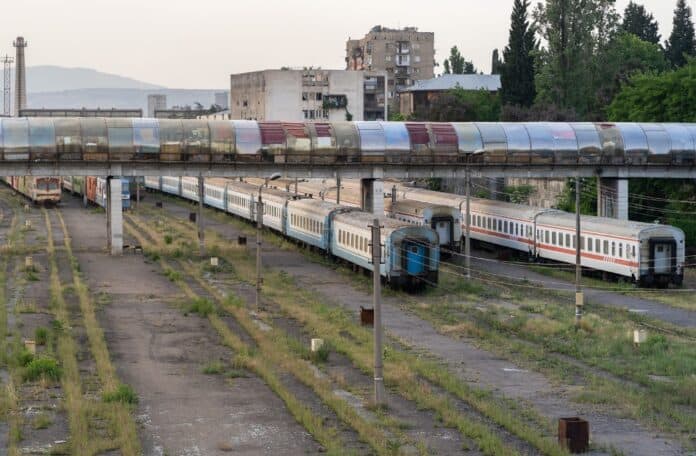 Οχήματα τρένων και σήραγγες σε εγκατάλειψη, εικόνα αστικού περιβάλλοντος με παλιές σιδηροδρομικές γραμμές και κτίρια.