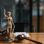 ΝΤΡΟΠΗ: 50.000 εποχικοί εργαζόμενοι όμηροι της κυβερνητικής ανικανότητας Ανθώπινη φιγούρα δικαστικής δικαιοσύνης με πενάκι, βιβλία και σφυρί στο γραφείο.