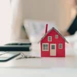 ΜΙΔΑ: Η νέα γραφειοκρατική θηλιά και το “κρυφό” φορολογικό κυνηγητό της κυβέρνησης – Η ΚΥΚΛΙΚΗ ΔΗΜΟΚΡΑΤΙΑ προειδοποιεί! Οικογενειακό σπίτι μικρό μοντέλο σε γραφείο με κλειδιά, συμβολίζει την κατοικία και την ασφάλεια.