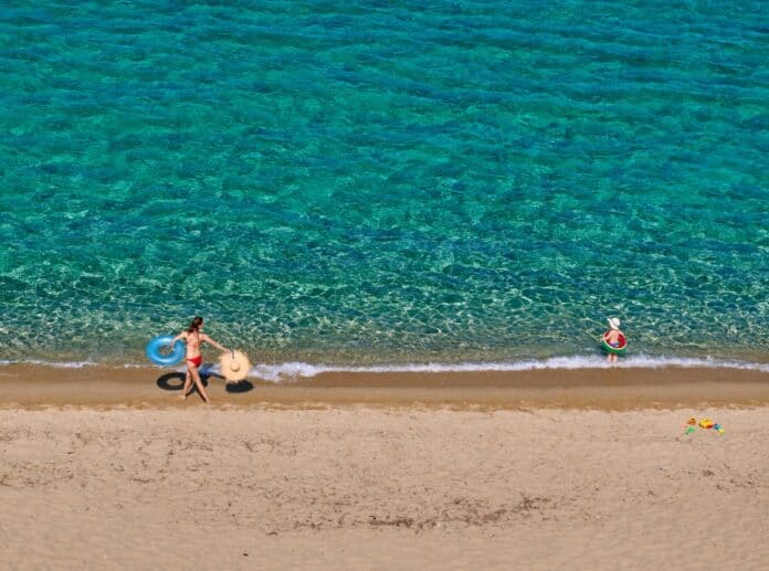 Κυκλική Δημοκρατία στη θάλασσα. Παιδιά απολαμβάνουν το καλοκαίρι στην παραλία με σωσίβια και παιχνίδια.