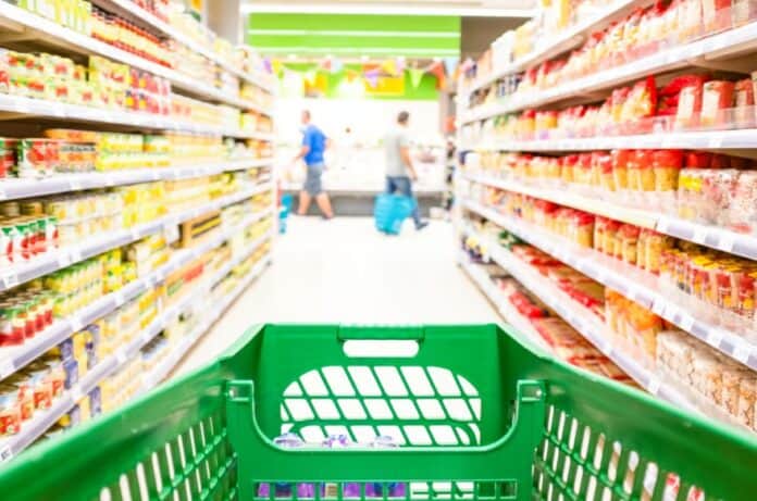 Ανθρώποι ψωνίζουν σε σούπερ μάρκετ, με επίκεντρο το πράσινο καλάθι αγορών, προωθώντας βιώσιμες πρακτ.