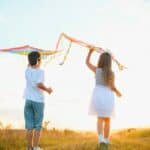 Η Πολιτισμική Γεωγραφία της Καθαρής Δευτέρας Χαρακτηριστικό στιγμιότυπο παιδιών που πετούν χαρταετούς στη φύση, συμβολίζοντας την πολιτισμική παρ.