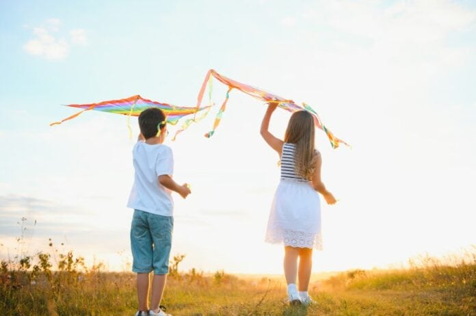 Ελεύθεροι παιδικοί παιχνίδι με χαρταετούς στην ύπαιθρο Χαρακτηριστικό στιγμιότυπο παιδιών που πετούν χαρταετούς στη φύση, συμβολίζοντας την πολιτισμική παρ.