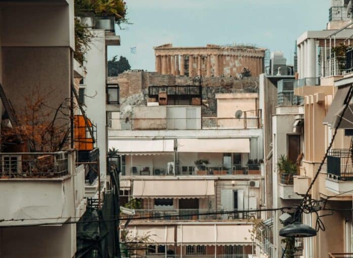 Ανθρώπινη πόλη με πολυκατοικίες και αρχαίο μνημείο στο βάθος.