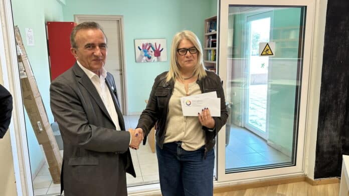 Άνδρας και γυναίκα ανταλλάσσουν χειραψία κατά την επίσκεψη της Κυκλικής Δημοκρατίας στο Ορφανοτροφεί.