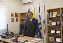 ΜΕ ΑΠΟΨΗ: Του Προέδρου ΚΥΚΛΙΚΗΣ ΔΗΜΟΚΡΑΤΙΑΣ κ. Ηλία Βασιλάκη Ανδρας σε γραφείο με ελληνικές σημαίες, εκπροσωπώντας την Κυκλική Δημοκρατία.